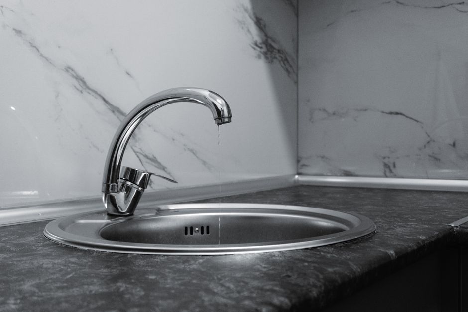 Idraulico che ripara un rubinetto sotto il lavello di un bagno