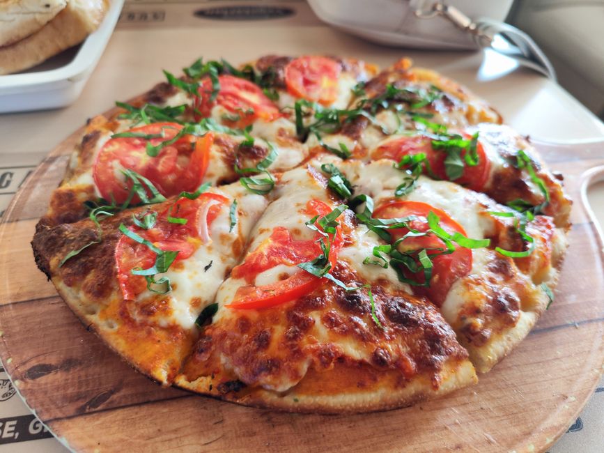 Pizza margherita con basilico fresco su tavolo di legno